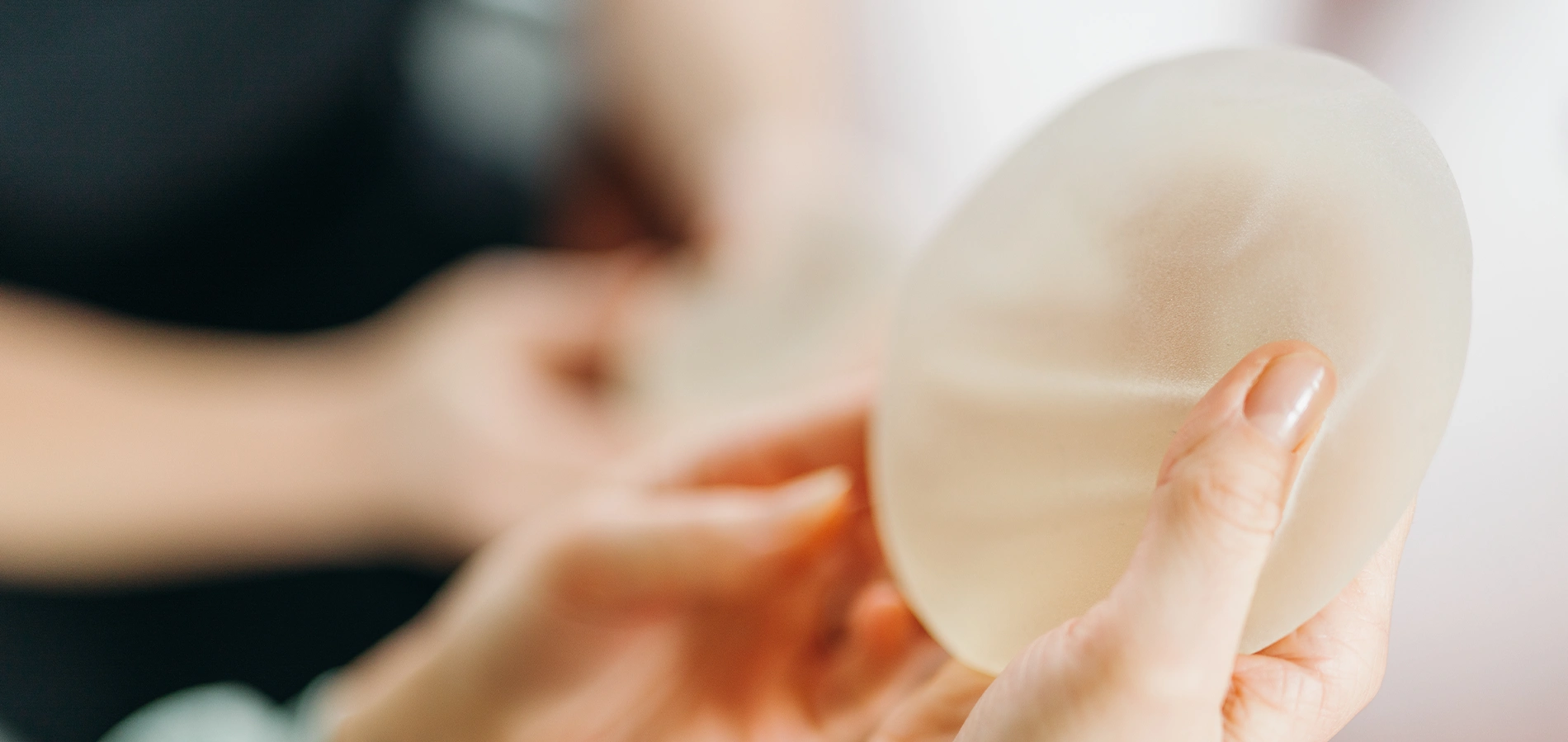 Brustimplantat in der Hand haltend